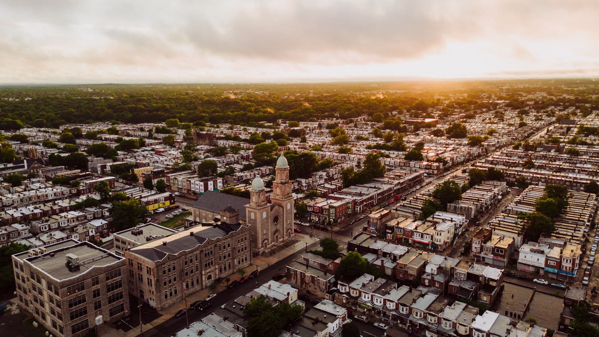 Aerial view of Philadelphia row home streets at sunrise, with a twin towered stone church